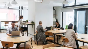 Personas trabajando en una cafetería luminosa.