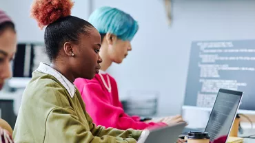 Personas trabajando en computadoras portátiles en una oficina.