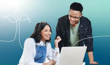 Dos personas sonriendo mientras miran una computadora portátil.